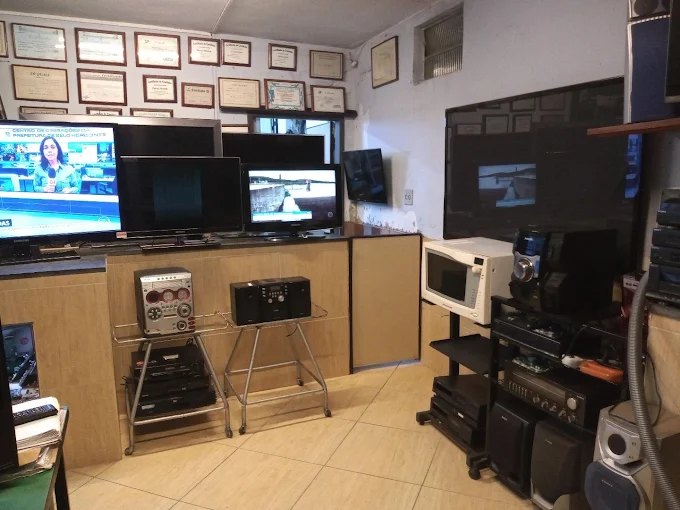 Interior da loja com TVs, monitores, micro-ondas e aparelhos de som na bancada