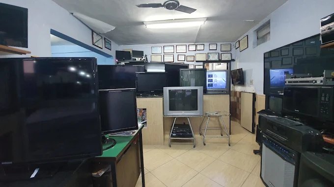 Salão da loja com TVs, monitores e aparelhos de som em manutenção